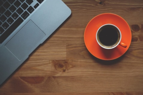 Computer keyboard next to a cup of coffee